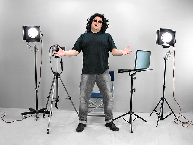 A guy standing in the middle of a video camera and video lights.